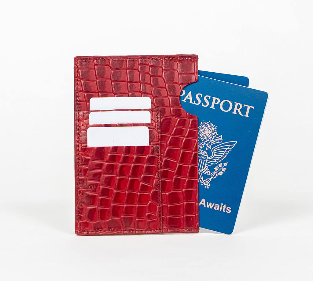 Red leather passport holder with a blue passport on a white background