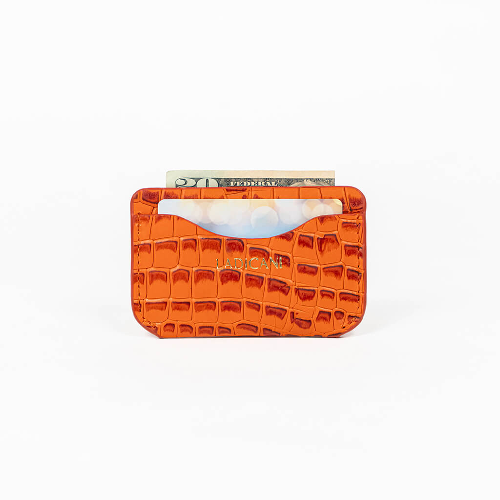 Orange leather slim wallet with money, a card, and branding on a white background