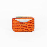 Orange leather slim wallet with money, a card, and branding on a white background