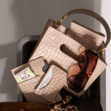 Beige handbag with sunglasses, passport cover and cardholder on a gray surface