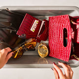 Red handbag with sunglasses, passport cover and cardholder on a gray surface
